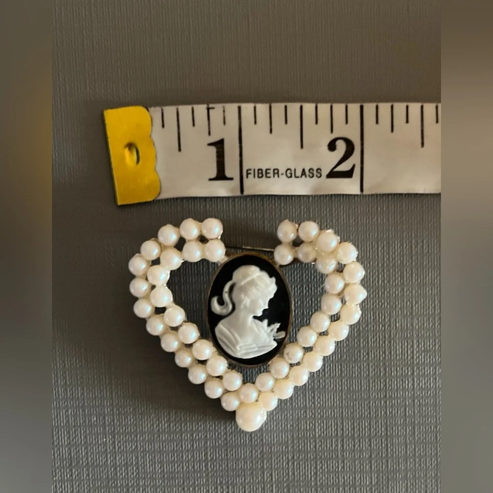 Vintage heart-shaped brooch featuring a black and white cameo with faux pearls.
